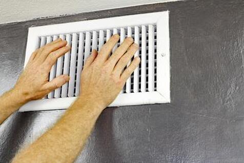 a pair of hands reaching up to feel that no cool air is emerging from their vent